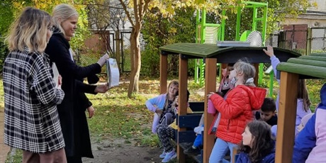 Powiększ grafikę: Na zdjęciu dziewczyny z organizacji "Topomole" prowadzące zajęcia czytelnicze z grupą dzieci w "Lokomotywie" na szkolnym placu zabaw.